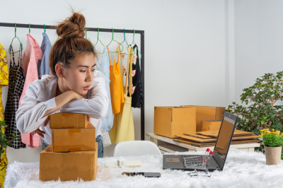 Vendedora mirando preocupada una pila de cajas frente a su laptop, destacando cómo TikTok Shop reduce el abandono del carrito y mejora la conversión.