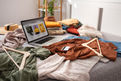 Tienda online abierta en una laptop rodeada de ropa, simbolizando la posibilidad de vender sin conocimientos técnicos ni una web propia.